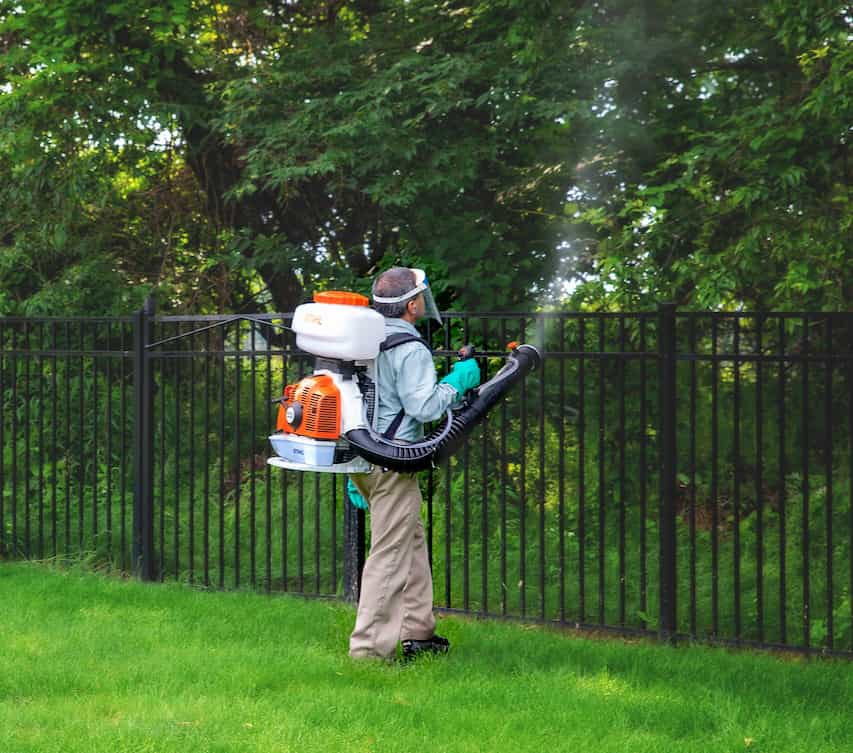 Technician applying mosquito application to woodline.